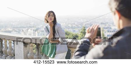 Stock Image - Man photographing girlfriend with Paris in background. Fotosearch