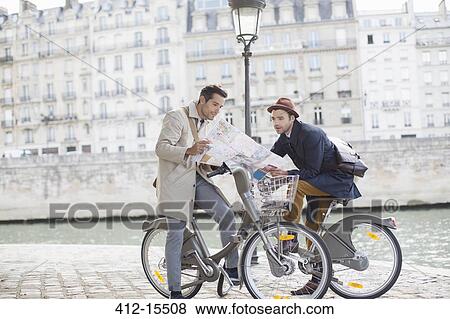 Stock Photo - Men on bicycles reading map along Seine River, Paris, France. Fotosearch