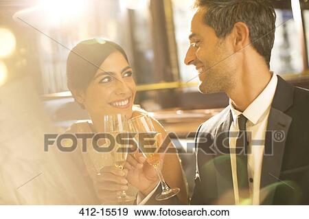Stock Photo - Well-dressed couple toasting champagne flutes in restaurant. Fotosearch