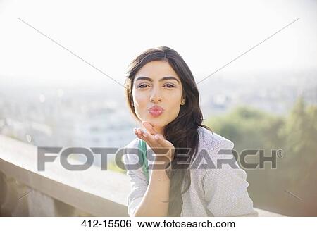 Stock Photograph - Woman blowing a kiss outdoors. Fotosearch