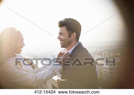 Picture - Woman holding boyfriend's collar on urban balcony. Fotosearch