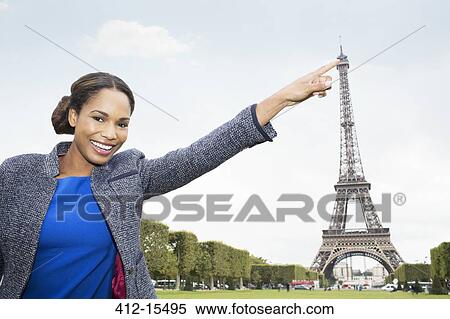 Stock Photography - Woman posing as if to touch Eiffel Tower, Paris, France. Fotosearch