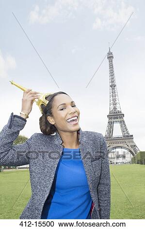 Stock Image - Woman posing with souvenir in front of Eiffel Tower, Paris, France. Fotosearch