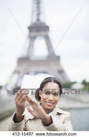 Stock Photo - Woman taking self-portrait in front of Eiffel Tower, Paris, France. Fotosearch