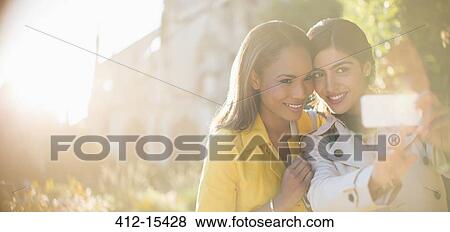 Women taking self-portrait with camera phone in garden View Large Photo Image Stock Photo - Women taking self-portrait with camera phone in garden. Fotosearch