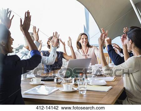 Stock Image - Business people cheering in meeting. Fotosearch