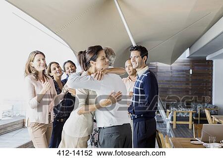 Stock Image - Business people hugging in office. Fotosearch