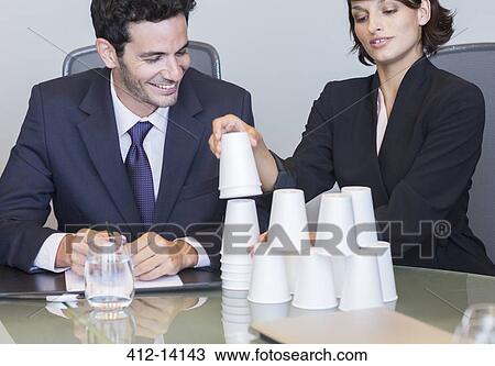 Stock Image - Business people stacking cups in meeting. Fotosearch