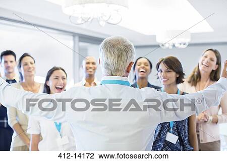 Businessman greeting enthusiastic colleagues in office View Large Photo Image Stock Image - Businessman greeting enthusiastic colleagues in office. Fotosearch