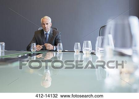 Stock Image - Businessman sitting at meeting table. Fotosearch
