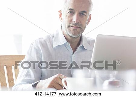 Stock Photo - Businessman using laptop in cafe. Fotosearch