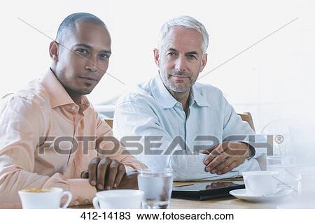Stock Image - Businessmen using digital tablet in cafe. Fotosearch