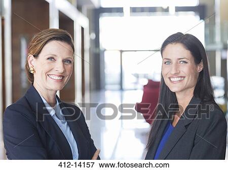 Stock Photo - Businesswomen smiling in lobby. Fotosearch