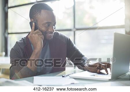 Businessman talking on cell phone and using laptop View Large Photo Image Stock Photo - Businessman talking on cell phone and using laptop. Fotosearch