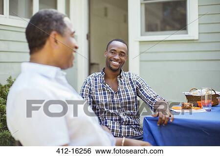 Stock Photograph - Father and son at patio table. Fotosearch