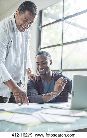 Father and son discussing paperwork at laptop View Large Photo Image Stock Photo - Father and son discussing paperwork at laptop. Fotosearch