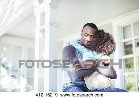 Stock Photo - Father hugging daughter on porch. Fotosearch