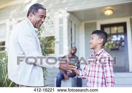 Stock Image - Grandfather and grandson exchanging special handshake outdoors. Fotosearch