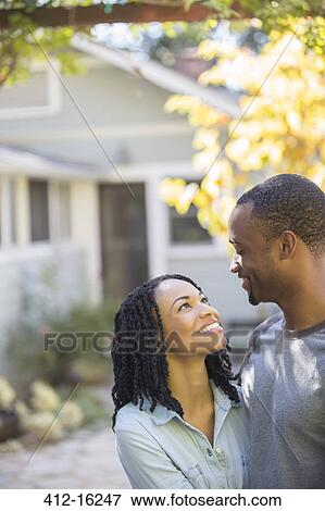 Happy couple hugging outside house View Large Photo Image Stock Photo - Happy couple hugging outside house. Fotosearch