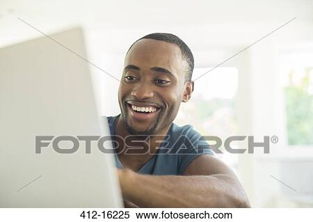 Stock Photography - Happy man using laptop. Fotosearch