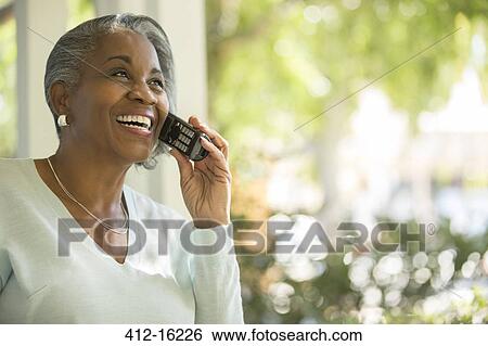 Stock Photograph - Happy senior woman talking on telephone outdoors. Fotosearch
