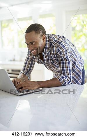 Man using laptop in kitchen View Large Photo Image Stock Photo - Man using laptop in kitchen. Fotosearch