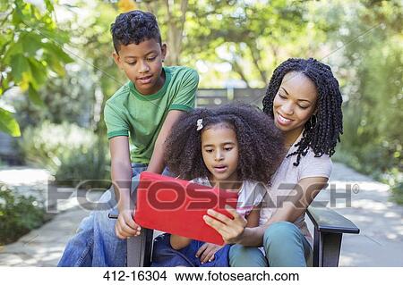 Mother and children using digital tablet outdoors View Large Photo Image Picture - Mother and children using digital tablet outdoors. Fotosearch