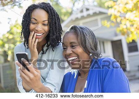 Mother and daughter looking at cell phone and laughing View Large Photo Image Stock Image - Mother and daughter looking at cell phone and laughing. Fotosearch