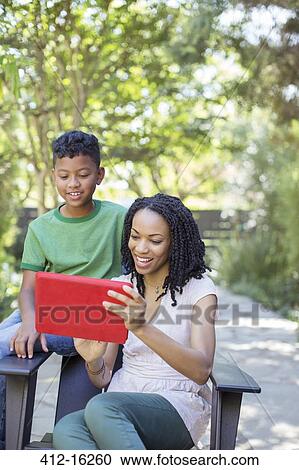 Stock Image - Mother and son using digital tablet outdoors. Fotosearch