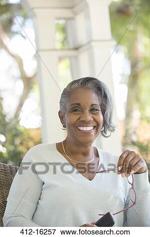 Portrait of happy senior woman holding eyeglasses outdoors View Large Photo Image Stock Photo - Portrait of happy senior woman holding eyeglasses outdoors. Fotosearch