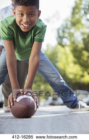 Stock Photography - Portrait of smiling boy preparing to snap football. Fotosearch