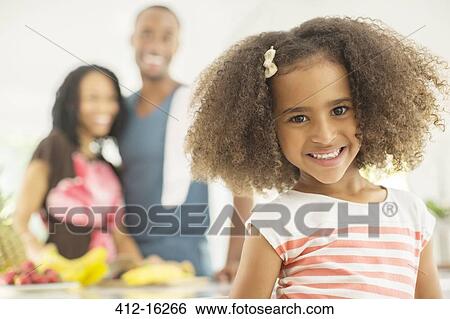 Portrait of smiling girl with parents in background View Large Photo Image Stock Photograph - Portrait of smiling girl with parents in background. Fotosearch