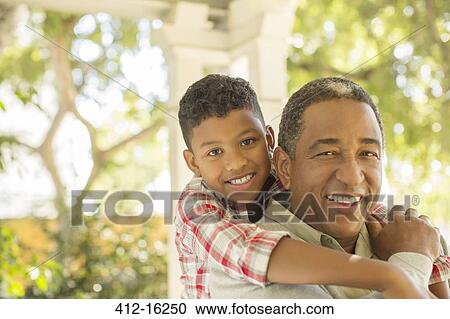 Stock Image - Portrait of smiling grandfather and grandson hugging outdoors. Fotosearch