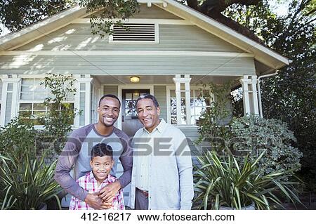 Stock Photo - Portrait of smiling multi-generation men outside house. Fotosearch
