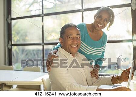 Stock Image - Portrait of smiling senior couple at laptop. Fotosearch