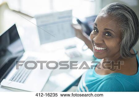 Portrait of smiling woman paying bills at laptop View Large Photo Image Stock Photography - Portrait of smiling woman paying bills at laptop. Fotosearch