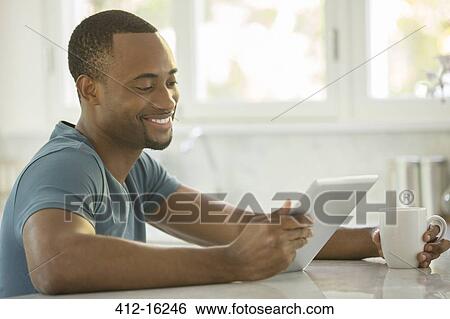 Stock Photograph - Smiling man drinking coffee and drinking coffee. Fotosearch