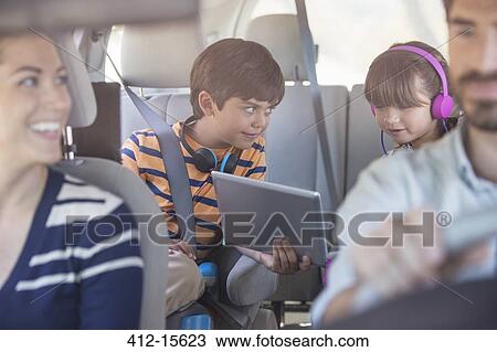 Brother and sister sharing digital tablet in back seat of car View Large Photo Image Stock Image - Brother and sister sharing digital tablet in back seat of car. Fotosearch
