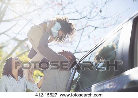 Father lifting daughter overhead outside car View Large Photo Image Stock Photo - Father lifting daughter overhead outside car. Fotosearch
