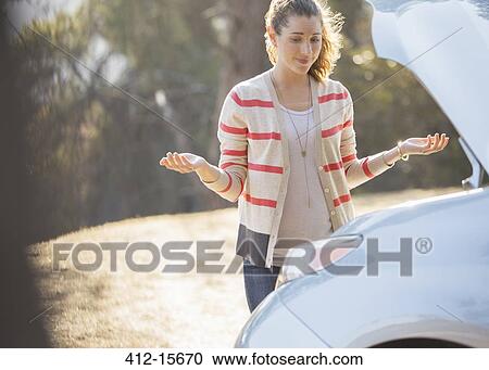 Frustrated woman looking at car engine at roadside View Large Photo Image Stock Image - Frustrated woman looking at car engine at roadside. Fotosearch