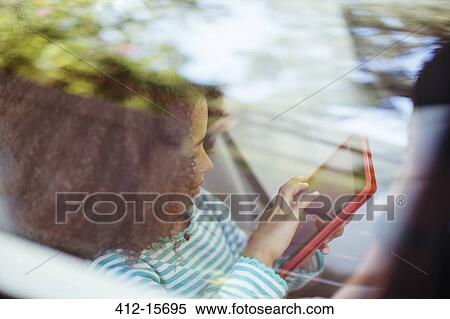Stock Photography - Girl using digital tablet in back seat of car. Fotosearch