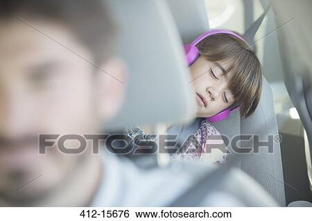 Stock Photograph - Girl with headphones sleeping in back seat of car. Fotosearch