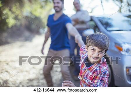 Picture - Happy boy dragging father by the arm outside car. Fotosearch