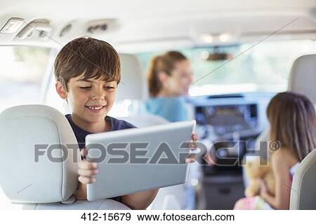 Happy boy using digital tablet in back seat of car View Large Photo Image Stock Photo - Happy boy using digital tablet in back seat of car. Fotosearch