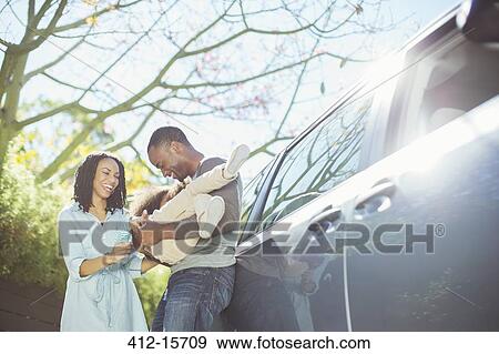 Stock Photo - Happy family outside car. Fotosearch