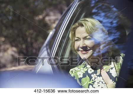 Happy senior woman looking at car window View Large Photo Image Stock Photograph - Happy senior woman looking at car window. Fotosearch