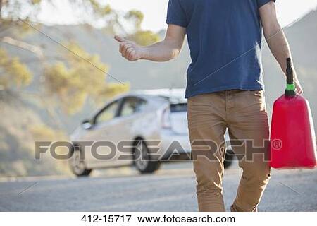 Stock Photo - Man with gas can hitchhiking at roadside. Fotosearch