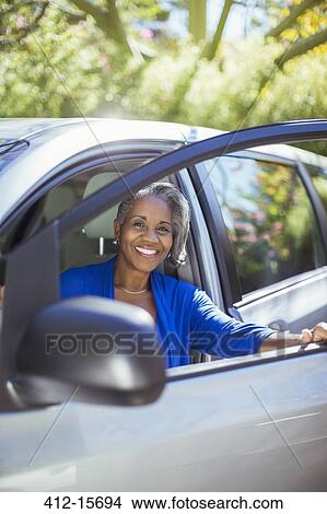 Picture - Portrait of confident senior woman getting out of car. Fotosearch