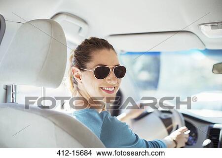 Picture - Portrait of confident woman in sunglasses driving car. Fotosearch