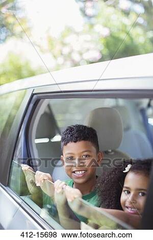 Portrait of happy brother and sister leaning out car window View Large Photo Image Stock Photo - Portrait of happy brother and sister leaning out car window. Fotosearch